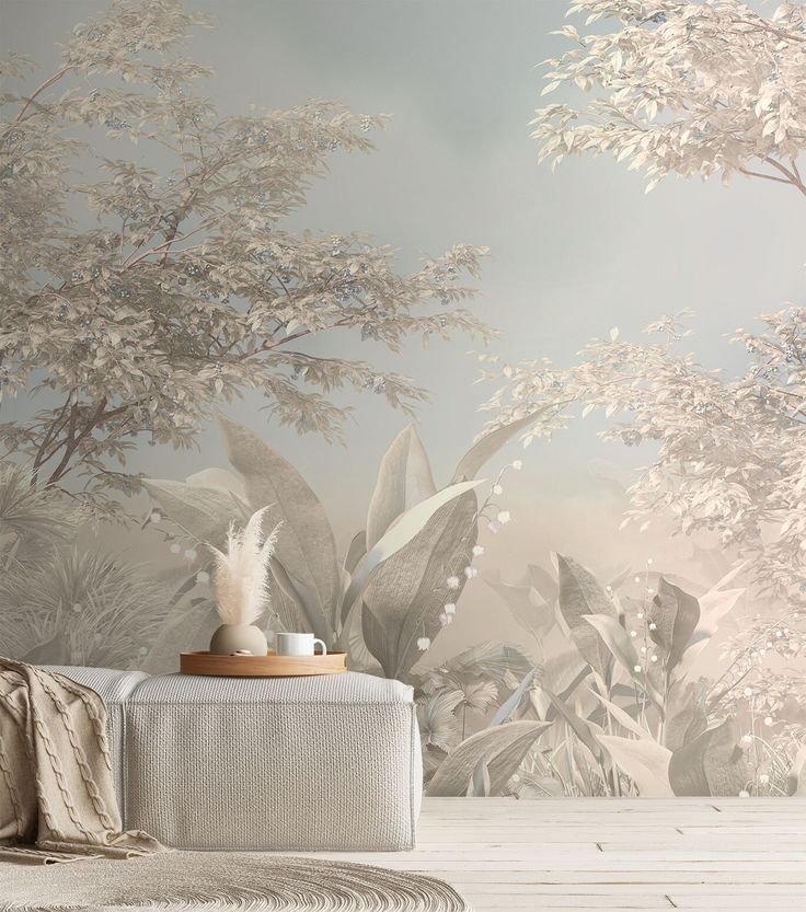 a white couch sitting in front of a wall mural with trees and plants on it