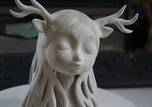 a white ceramic sculpture of a woman's head with horns on top of it