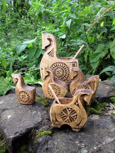 a wooden toy horse and carriage sitting on top of a rock in the woods next to some plants