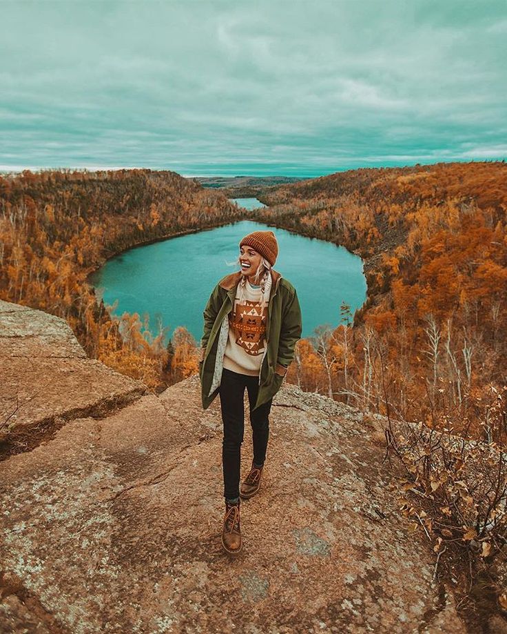 a man standing on top of a cliff next to a lake