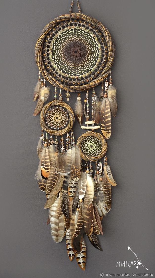 a decorative wall hanging with feathers and beads on it's side, in the shape of a dream catcher