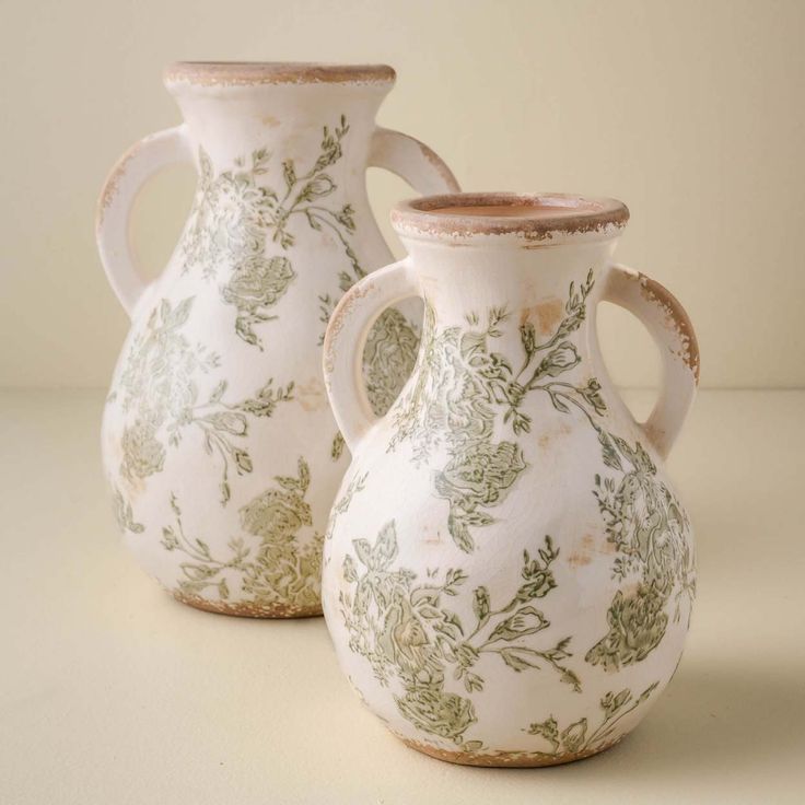 two white vases sitting next to each other on a table