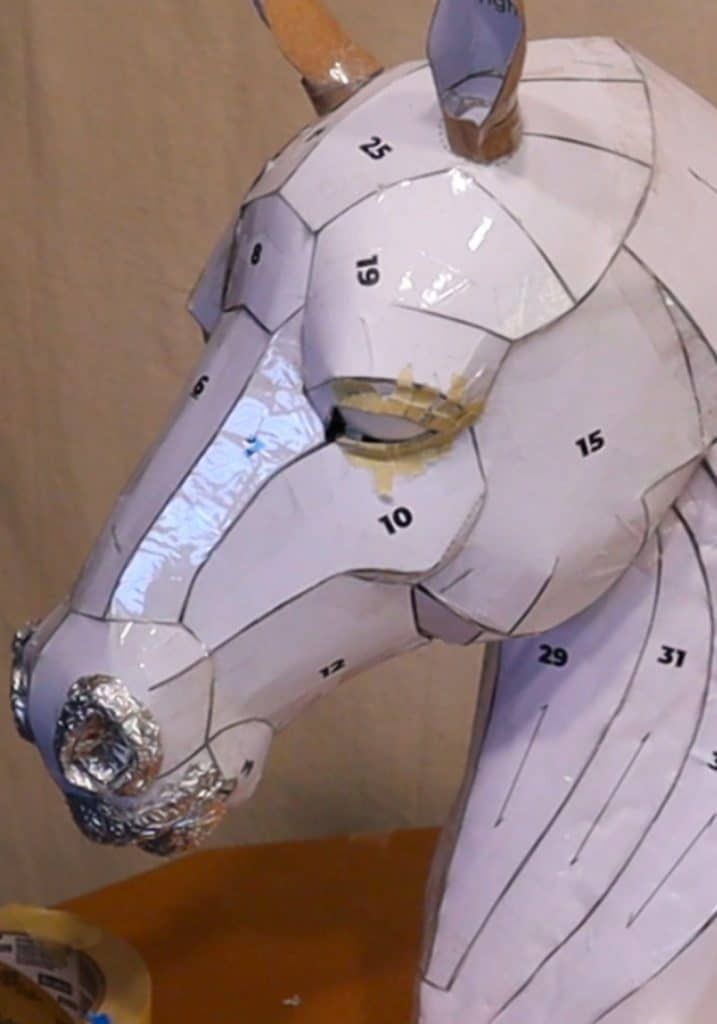 a paper mache horse head with numbers on it's face and neck, sitting on a table