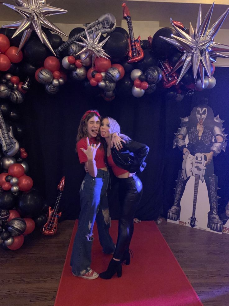 two women hugging each other on a red carpet in front of balloons and star decorations