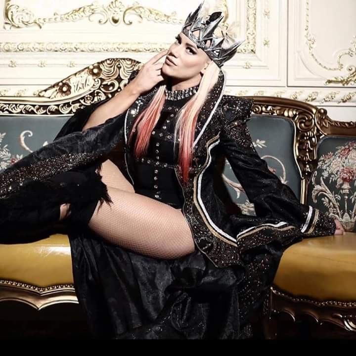 a woman sitting on top of a couch wearing a black dress and a silver crown