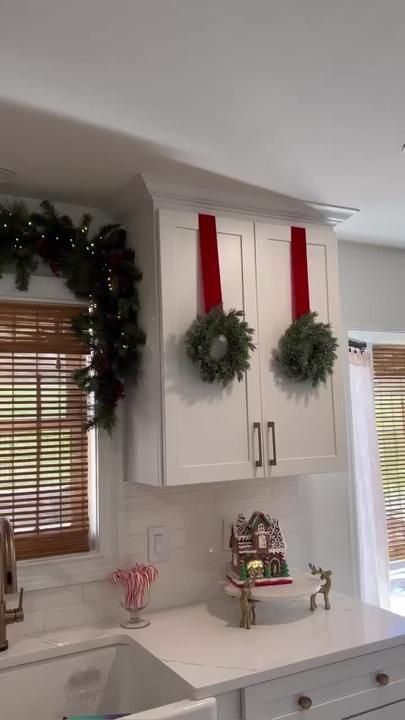 a kitchen decorated for christmas with wreaths on the cabinets