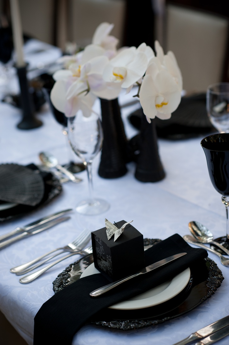 the table is set with black and white place settings, silverware, and flowers