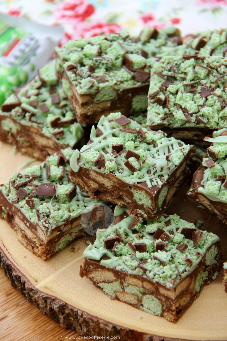 there are many pieces of cake on the wooden platter that is decorated with chocolate and green frosting