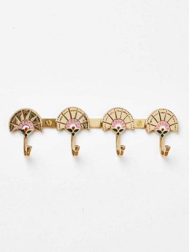 three gold - plated metal wall hooks with pink and green accents