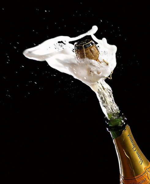 a bottle of champagne is being poured into the air with water splashing on it