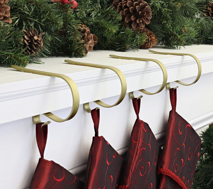 three christmas stockings hanging from hooks on a mantel