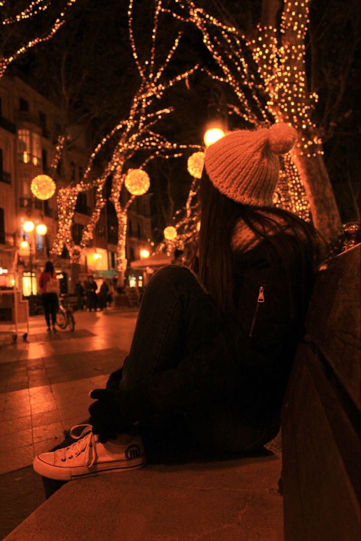 a person sitting on a bench in front of some lights