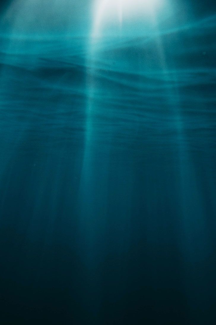 an underwater view of the ocean with sunlight shining through water's surface and light coming from above