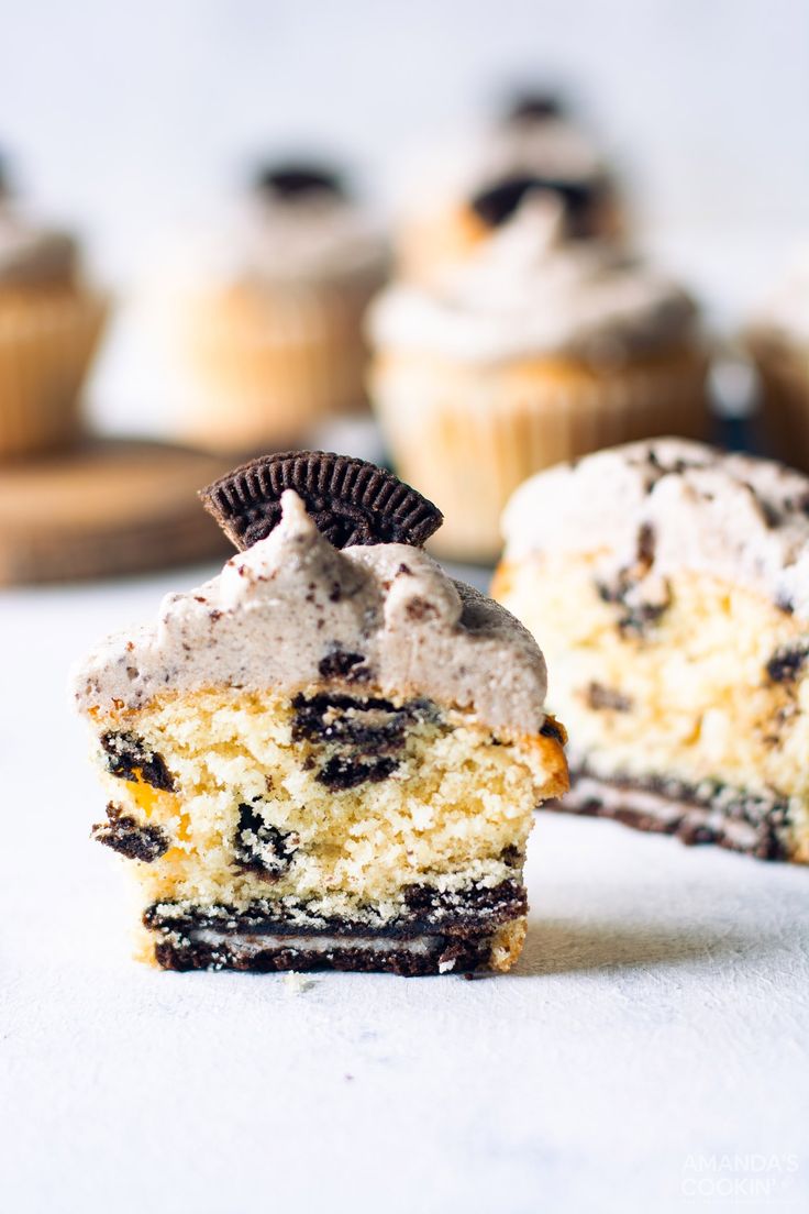 an oreo cookie cupcake with frosting and chocolate chips on top, sitting in front of other cupcakes