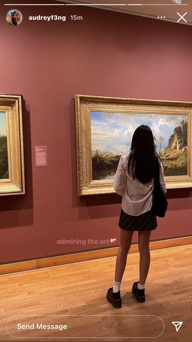 a woman looking at paintings on display in a museum