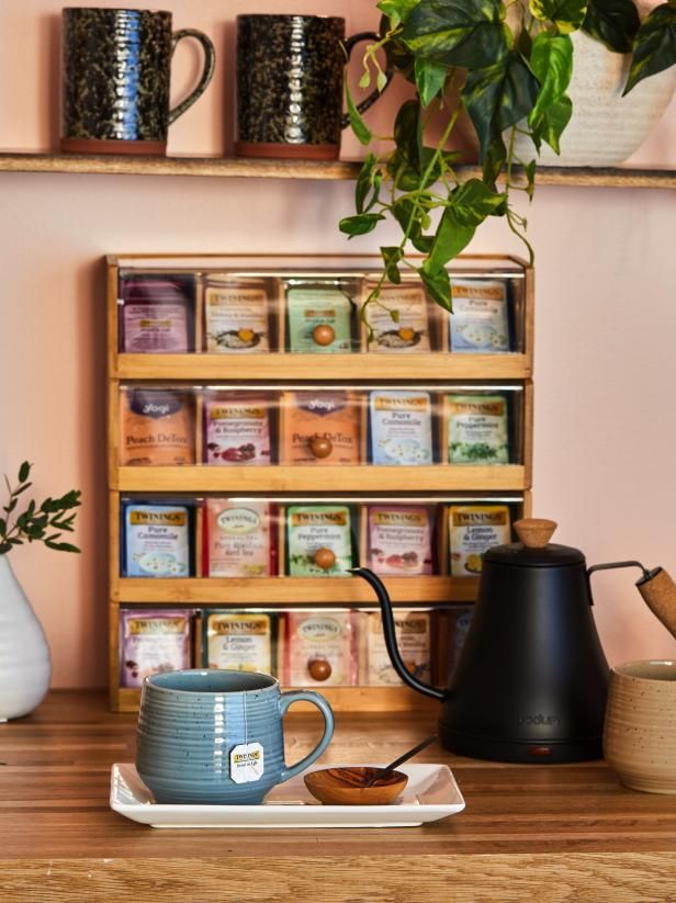 there is a coffee pot and cup on the table next to some tea cups with plants growing out of them