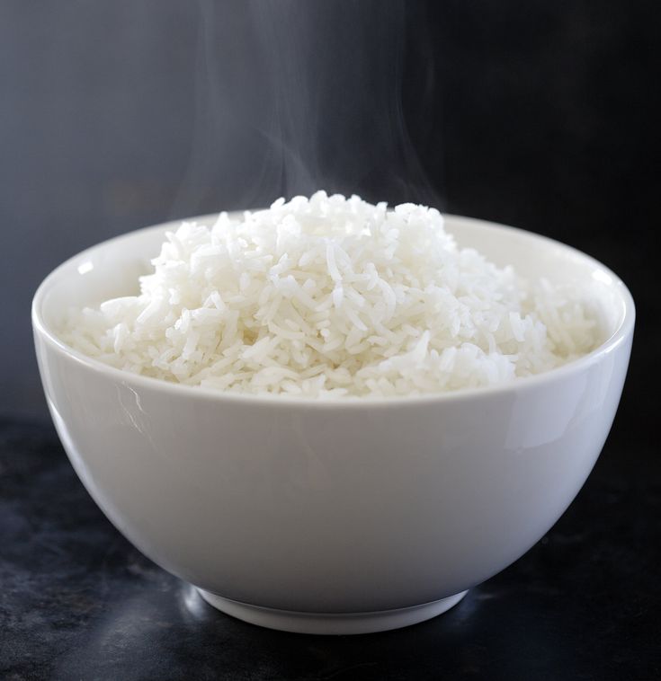 steaming rice in a white bowl on a black table