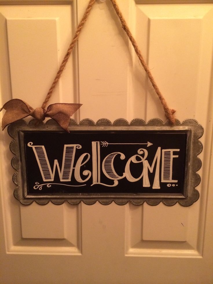 a welcome sign hanging on the front door with a bow around it's neck