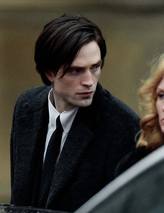 a man and woman standing next to each other in front of a car on the street