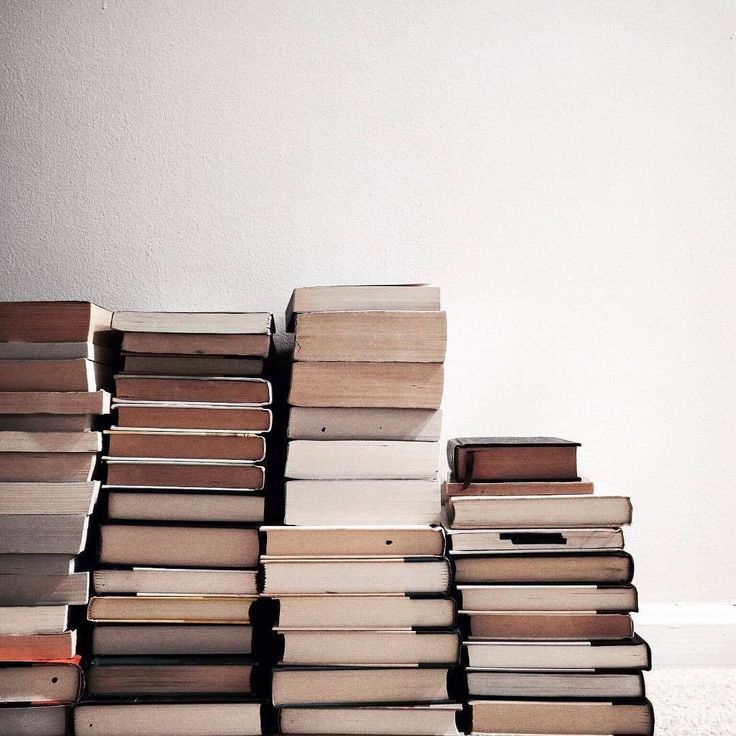 a stack of books sitting on top of each other in front of a white wall