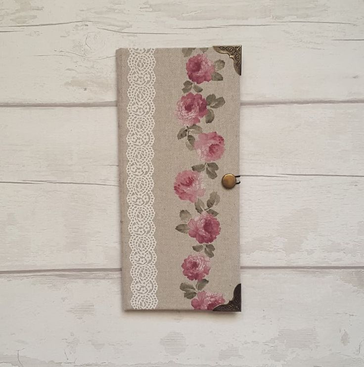 a book with pink flowers on it sitting on a white wooden table next to a button