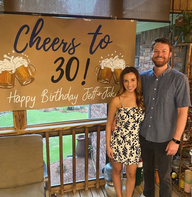 a man and woman standing in front of a sign that says cheers to 30 happy birthday self - date