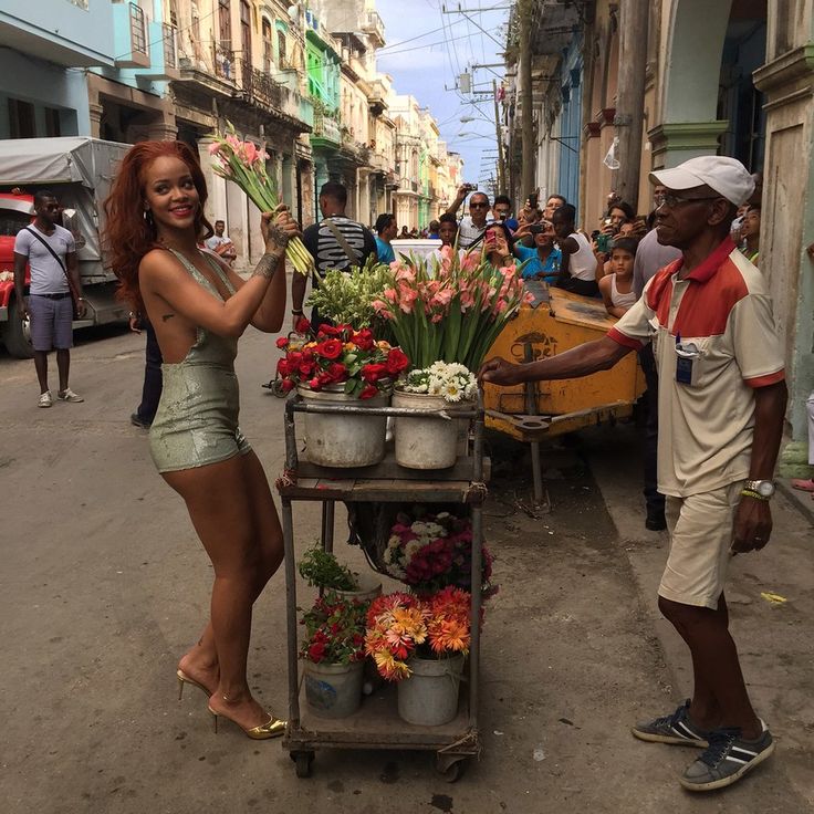 a woman standing next to a man in front of a cart filled with lots of flowers