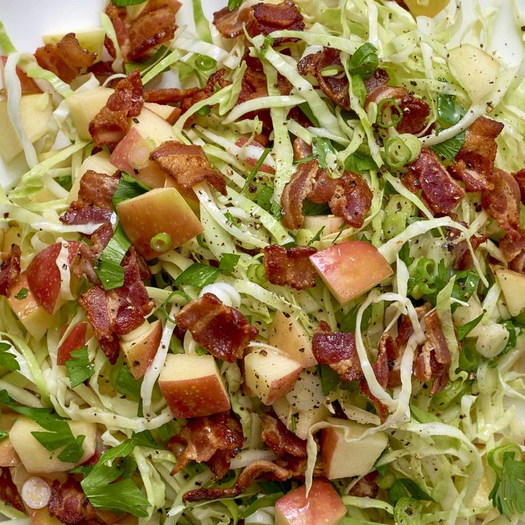 a salad with bacon, lettuce and apples in it on a white plate