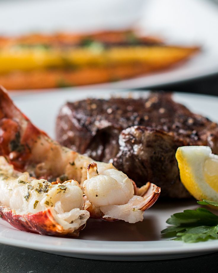 a plate with lobster, steak and lemon wedges