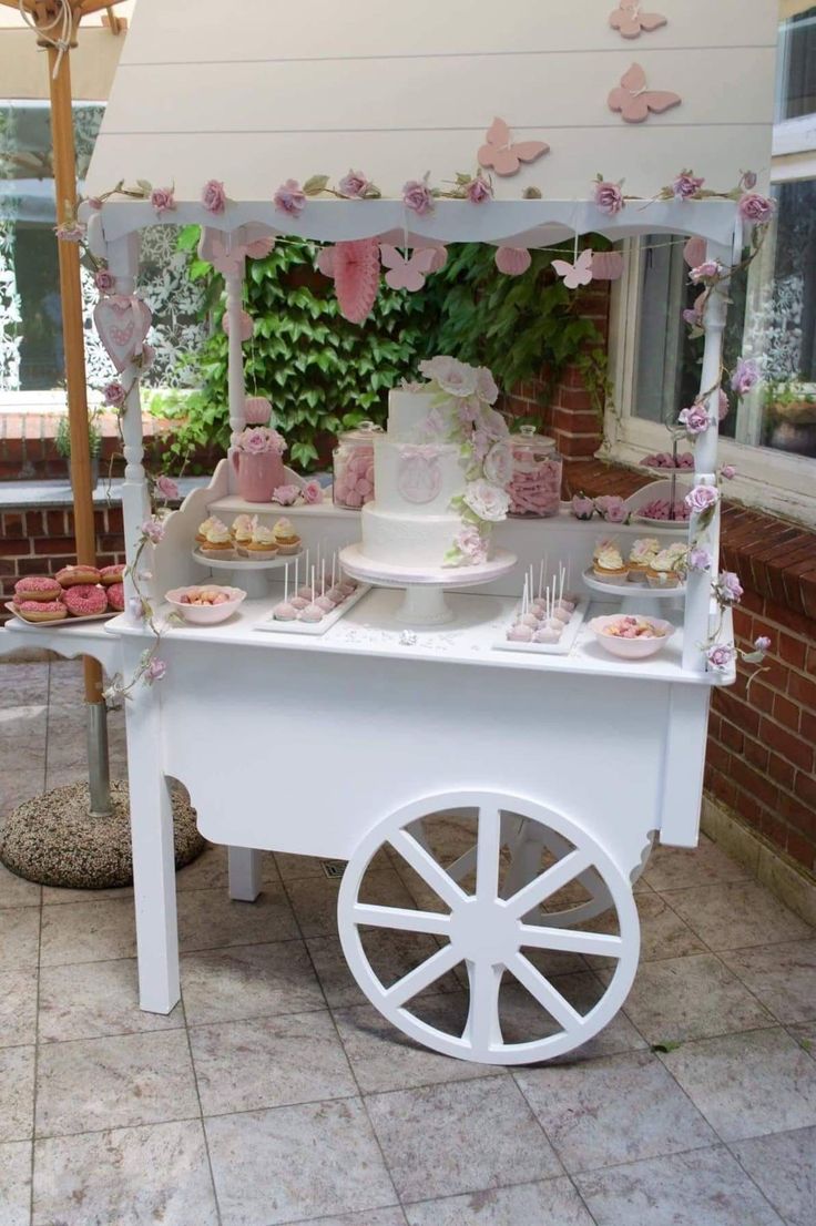 a white cart filled with lots of cupcakes on top of a stone floor