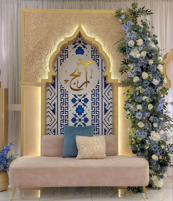 a couch sitting in front of a blue and white wall with an arabic calligraphy on it