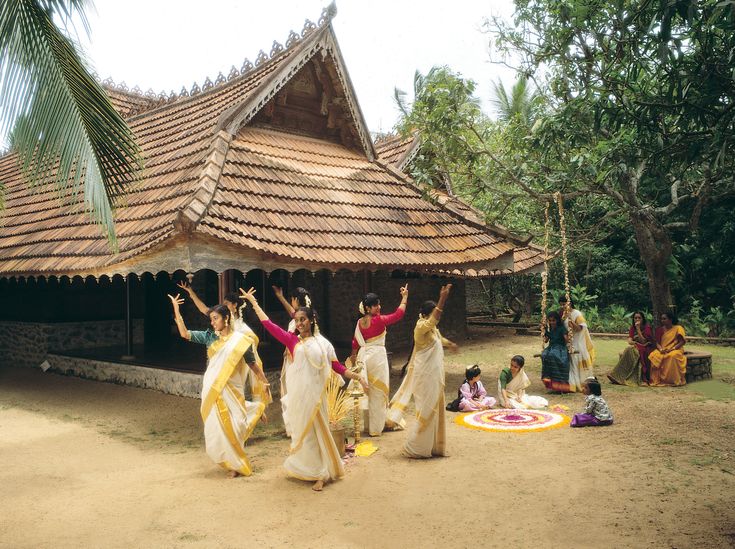 several women are dancing in front of a building with tiled roof and wooden shingles