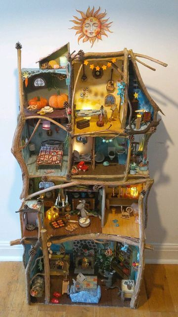 a doll house made out of wood with lots of toys on top of the shelves