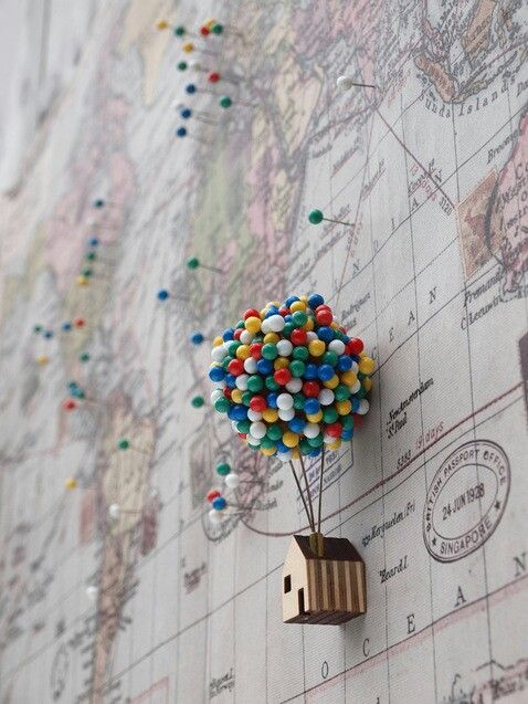 a small toy house with balloons attached to the back of it on top of a map