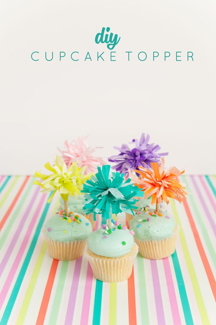 three cupcakes decorated with colorful flowers and sprinkles on a striped tablecloth