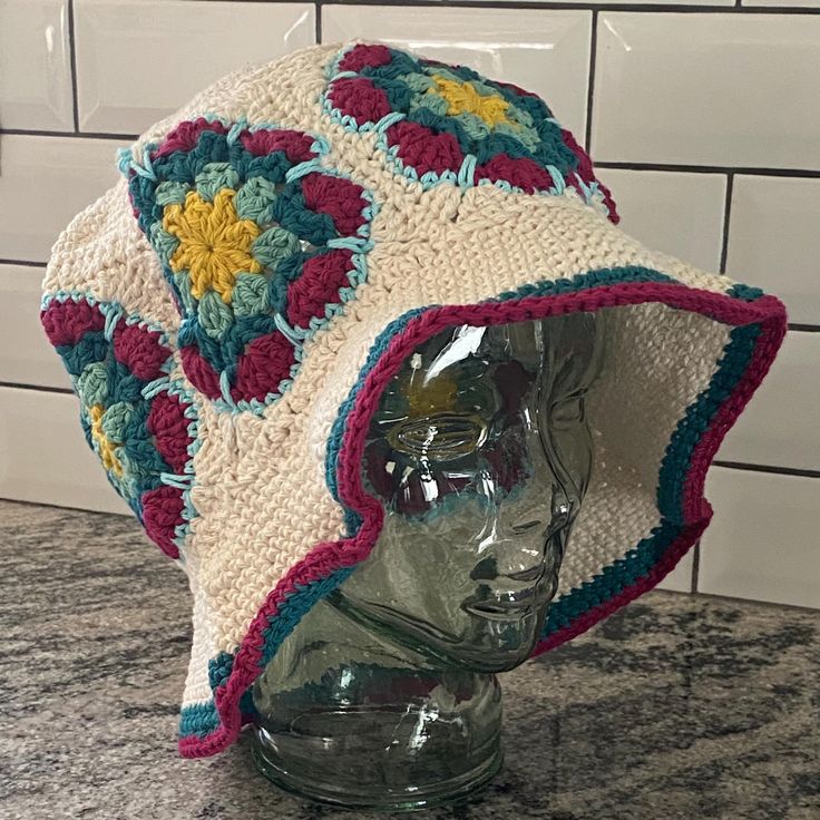 a crocheted hat on top of a glass head