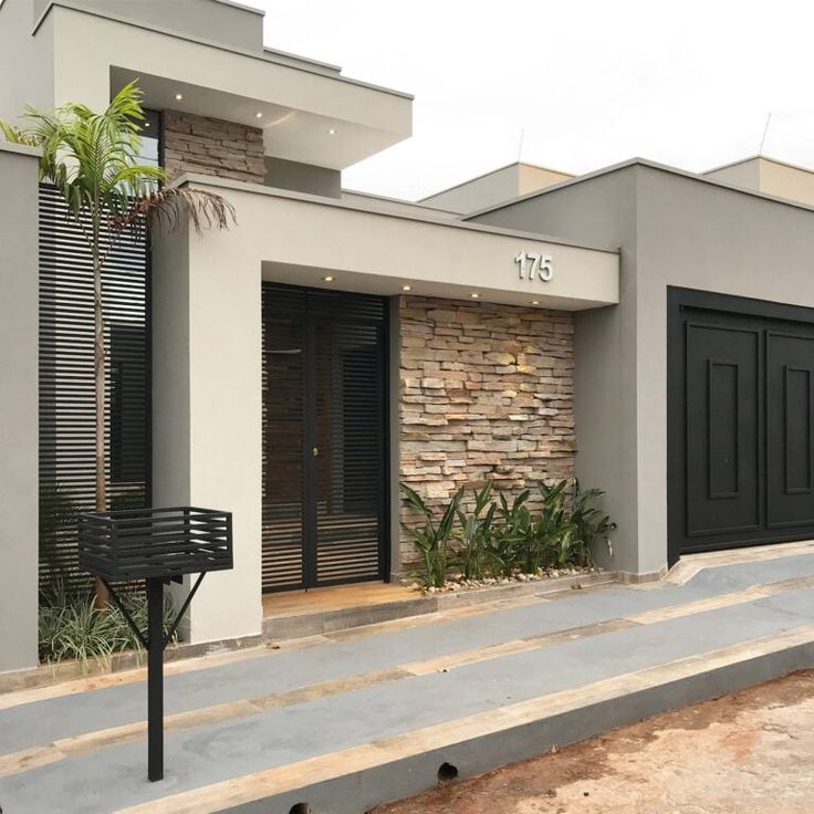 an empty street in front of a building with black garage doors and shutters on the windows