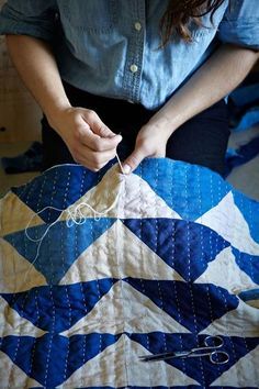 a woman is working on a quilt with scissors