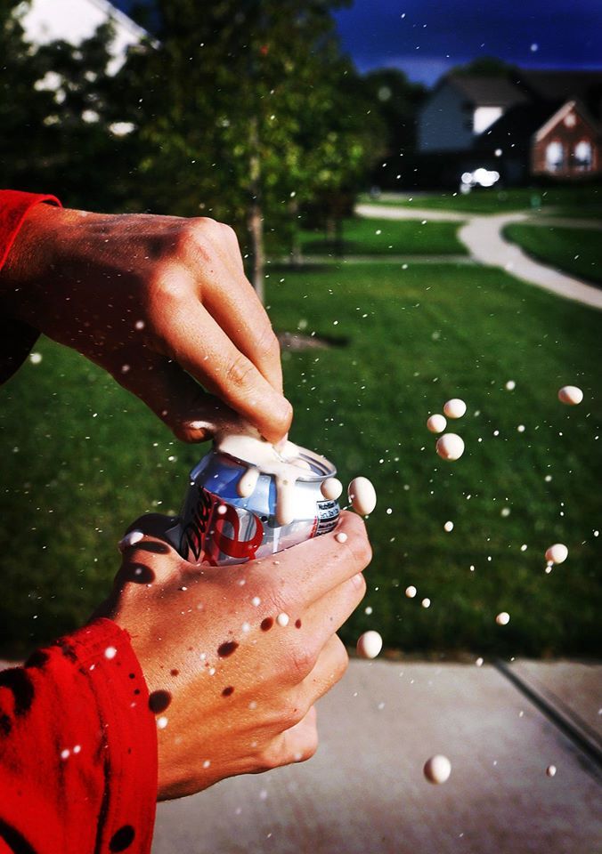 a person is throwing balls in the air and spraying them with something white on their face