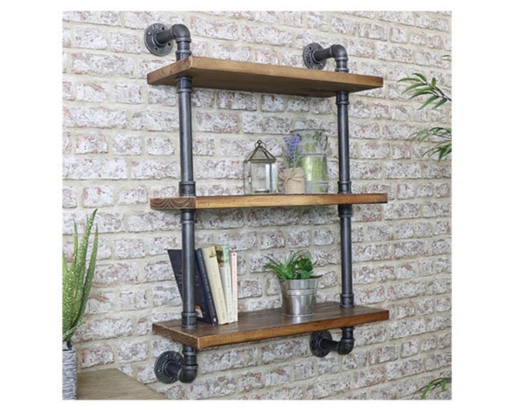 two wooden shelves with metal pipes and books on them next to a brick wall in a room