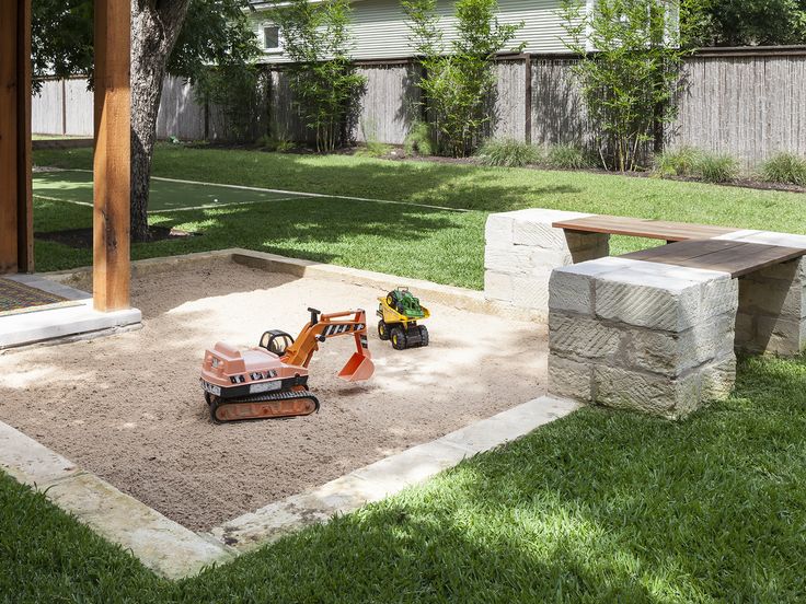 a small toy excavator in the middle of a yard with sand and grass