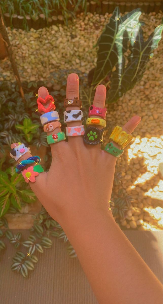 a hand with five finger rings decorated like cartoon characters