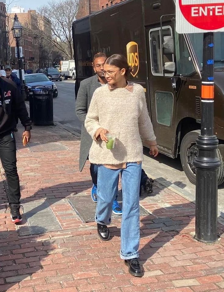 a woman walking down the street in front of a truck