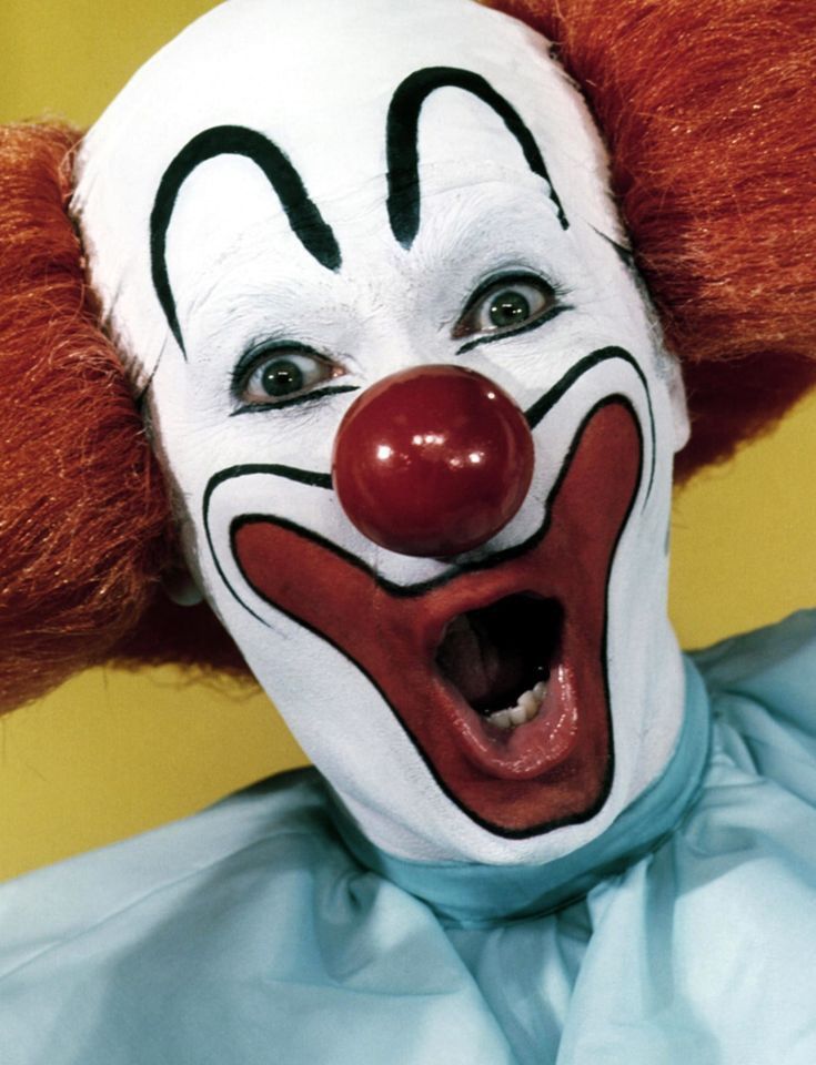 a clown with red hair and white face paint on it's head is making a funny face