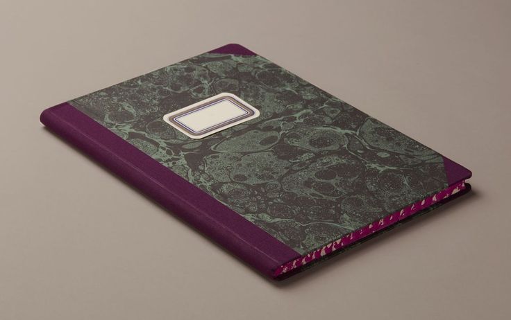 a purple and green book with a metal button on the front, sitting on a gray surface