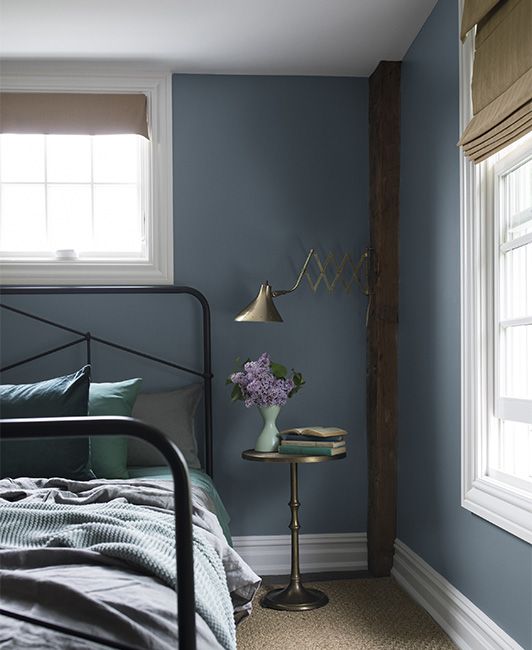 a bed room with a neatly made bed next to a window and a night stand