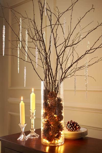 a vase filled with pine cones next to a candle and some candles on a table