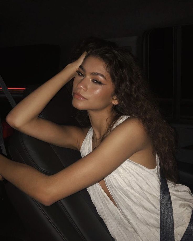 a woman sitting in the back seat of a car with her hand on her head