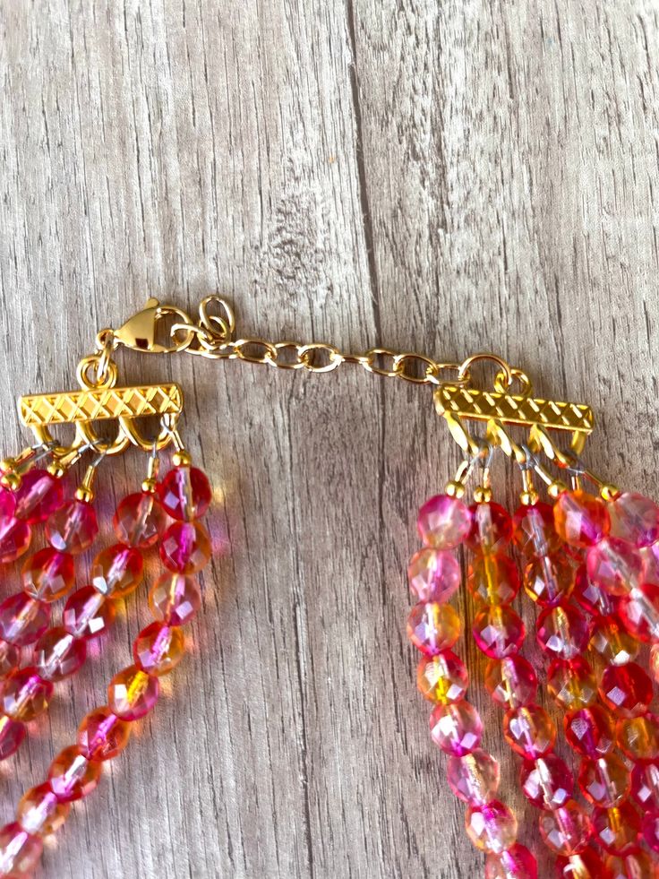 A gorgeous beaded statement necklace made with pink and orange faceted crystal beads. - 6 strands (more are listed)- Shortest strand measures 18.75 - 20.75" (will vary depending on clasp)- Gold stainless steel lobster claw (sterling silver, gold filled, stainless steel are also available) - 2" gold stainless steel extender chain- Lead free pewter multi strand connectorThe necklace length can also be customized. The mannequin's neck size is 14.5" for your reference. .A matching bracelet and earri Crystal Statement Necklace, Orange Crystals, Beaded Statement Necklace, Matching Bracelet, Multi Strand Necklace, Glass Bead Necklace, Faceted Crystal, Matching Bracelets, Pink Crystal