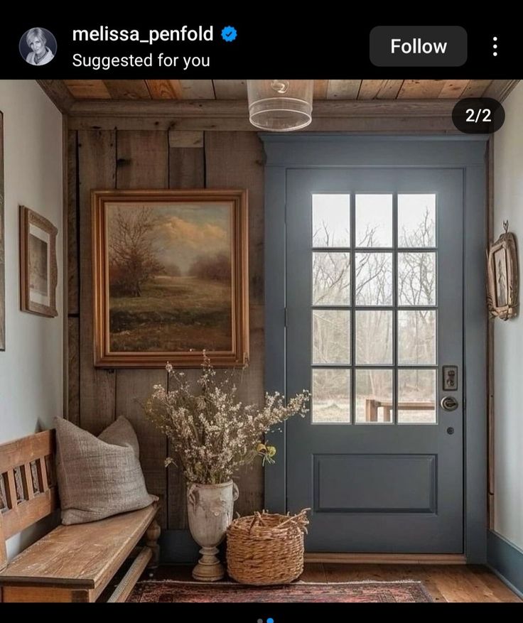 a blue front door with a wooden bench next to it and pictures on the wall